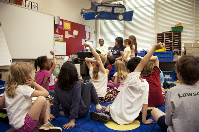 Kids sat on the floor of a classroom facing a teacher
