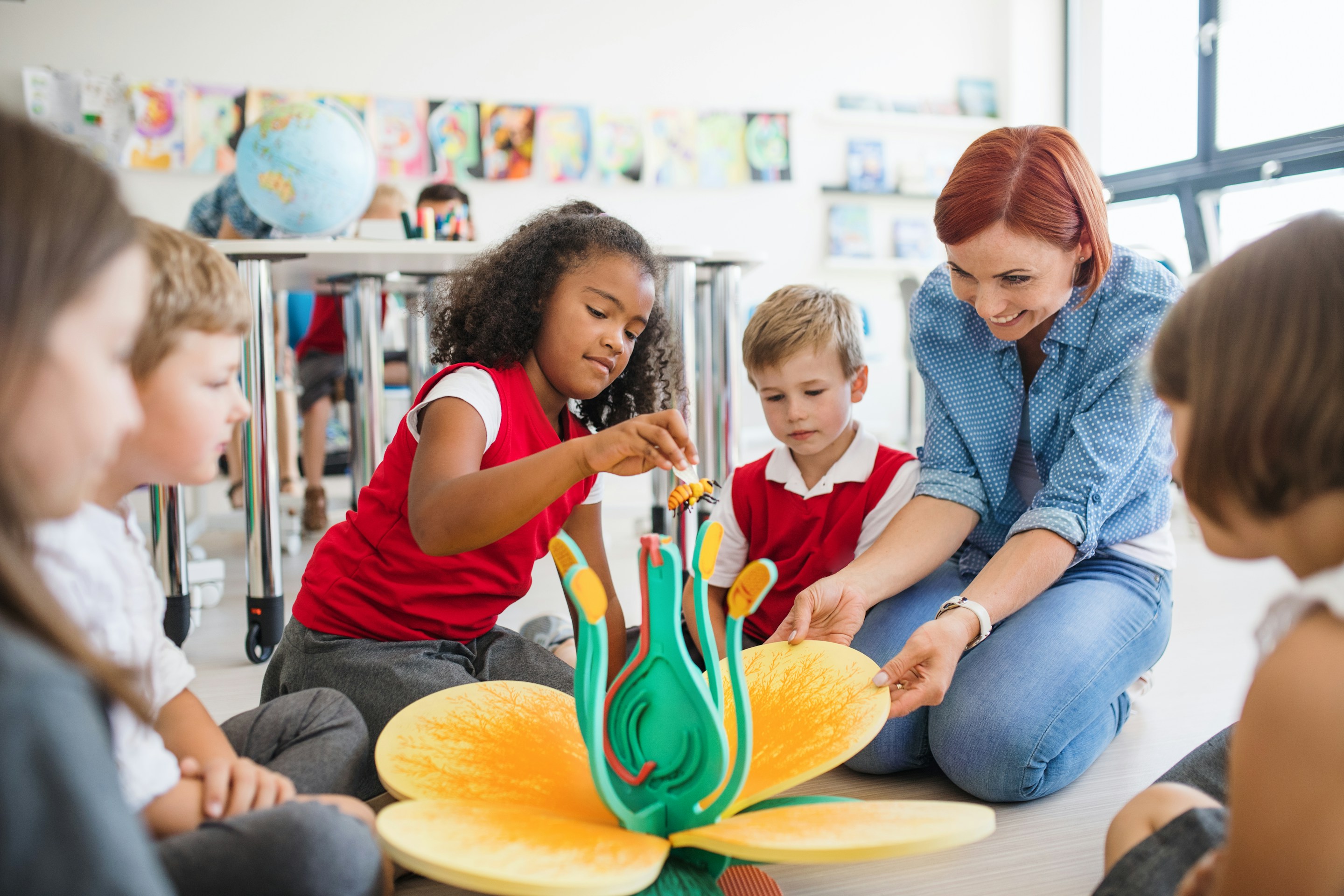 Children and teacher sitting around a plant